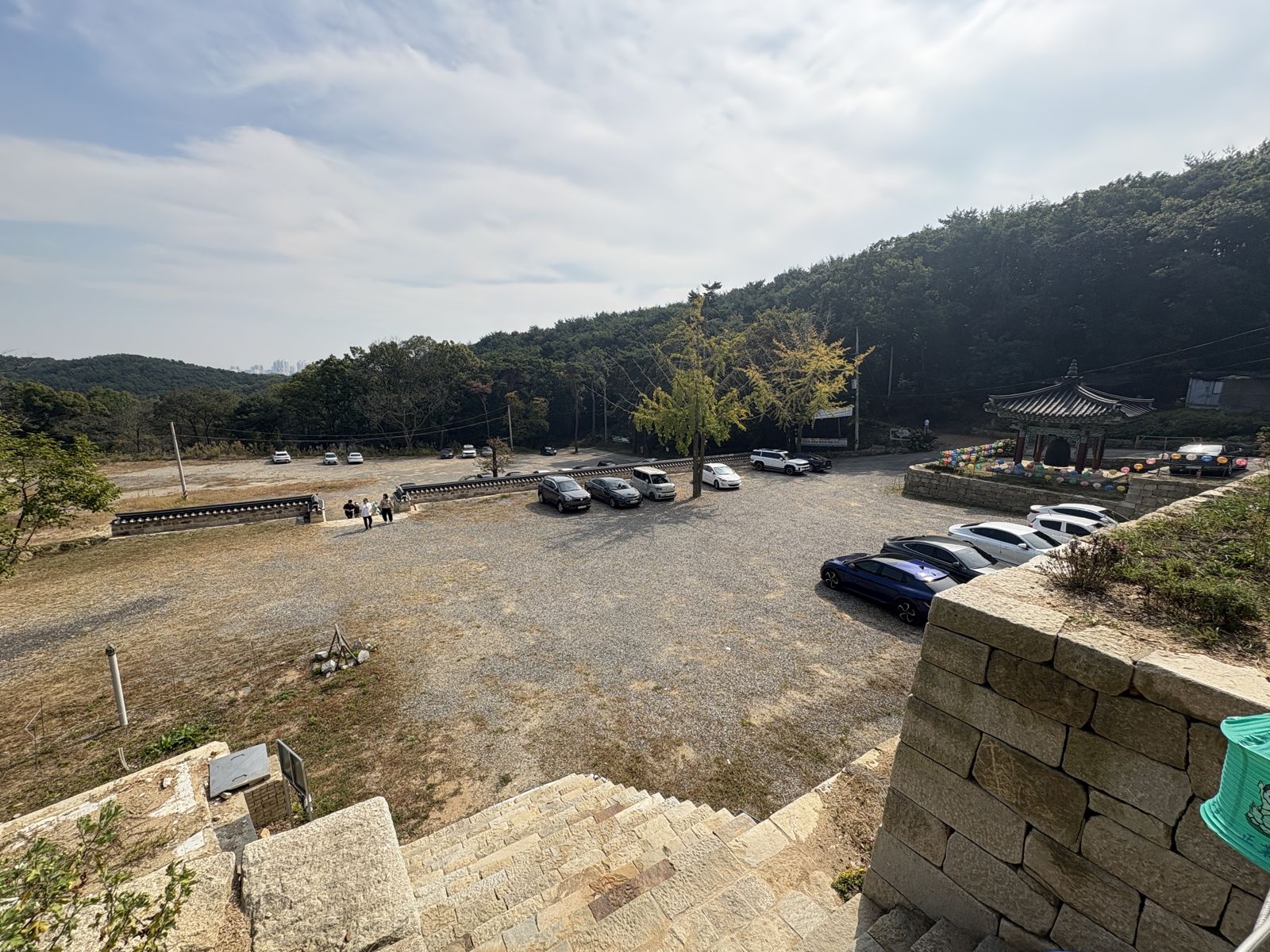 A large open parking area below the temple, with hills behind